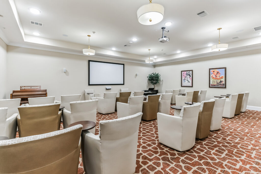 Interior image of the movie room with a big screen and lots of seating at Woodhaven Village, a senior living community near Montgomery, TX.