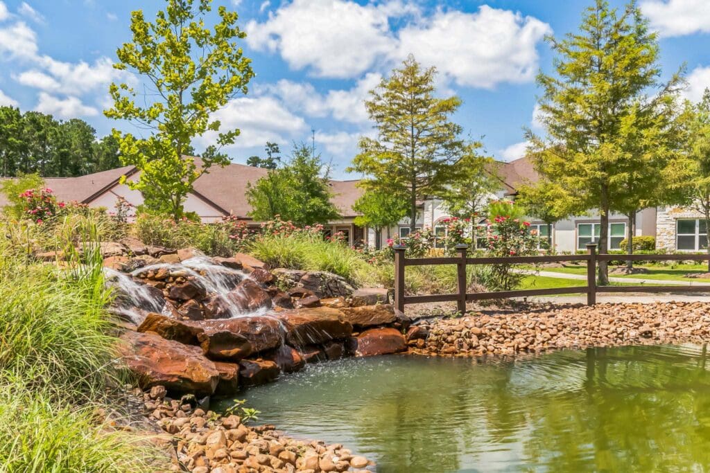 Exterior image of Woodhaven Village's beautiful foliage and man made pond.